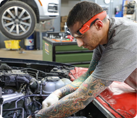 Mechanic wearing safety glasses repairs a car engine in an auto shop | Trask Automotive