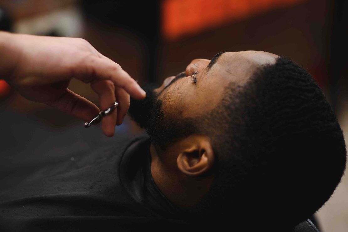 A man is getting his beard shaved at a barber shop.