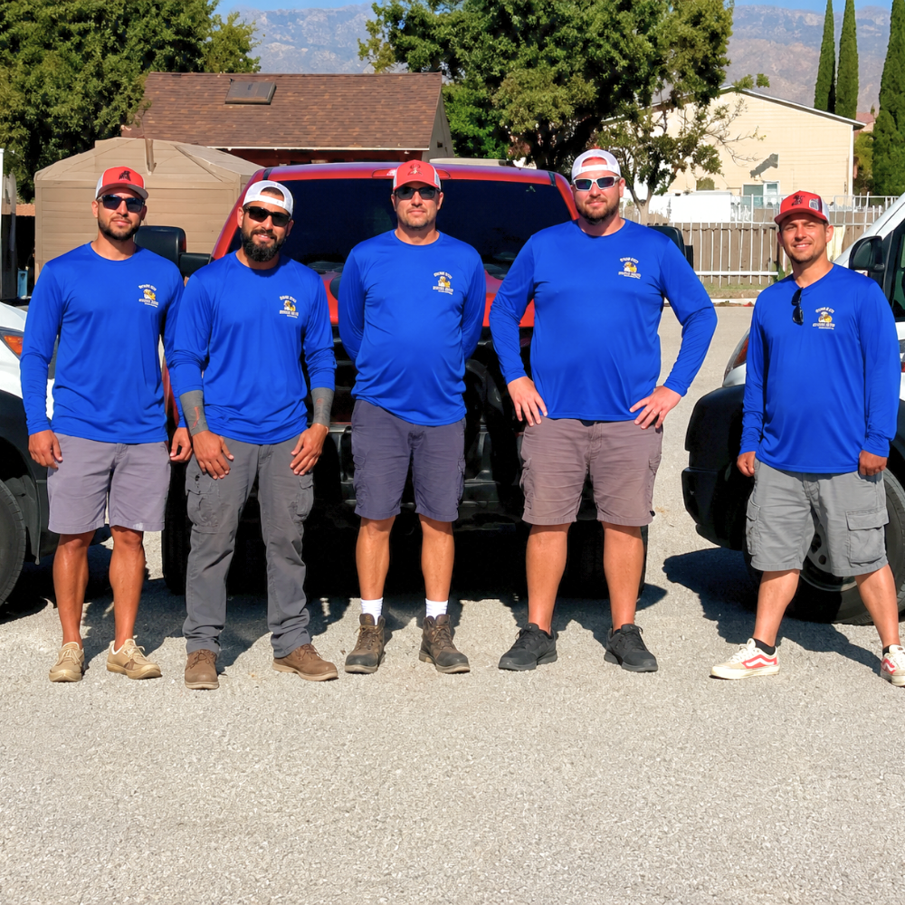 Five people in blue shirts and red caps standing outdoors in front of a red SUV.
