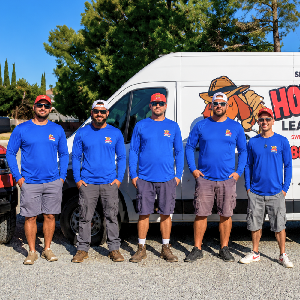 Five volunteers in blue shirts and red caps standing in front of a branded white van outdoors