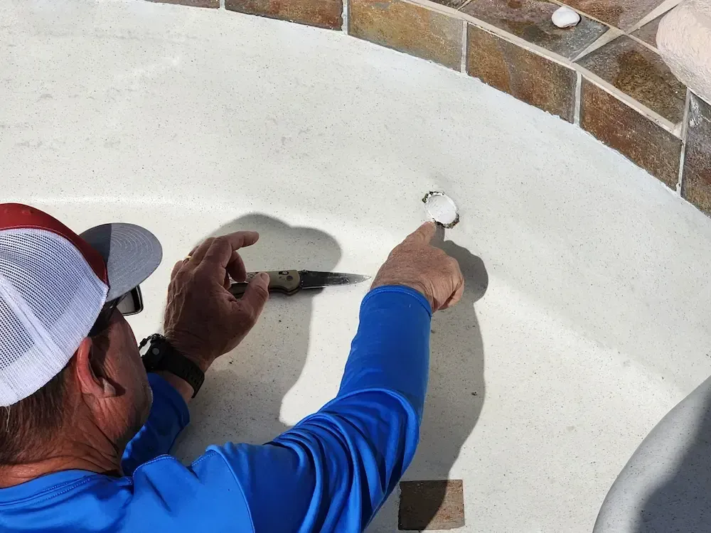 Worker drilling a hole in a white stucco wall near brick trim outdoors