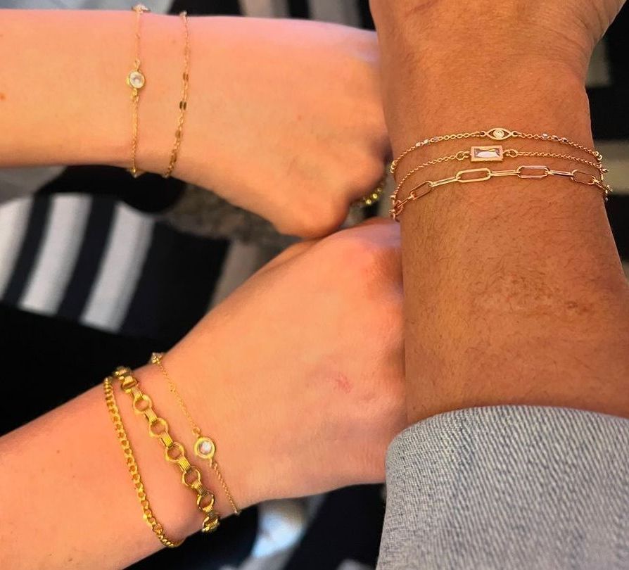 Two people wearing gold bracelets on their wrists