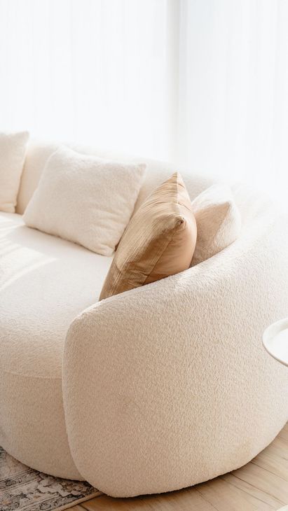 A white couch is sitting in a living room next to a window.