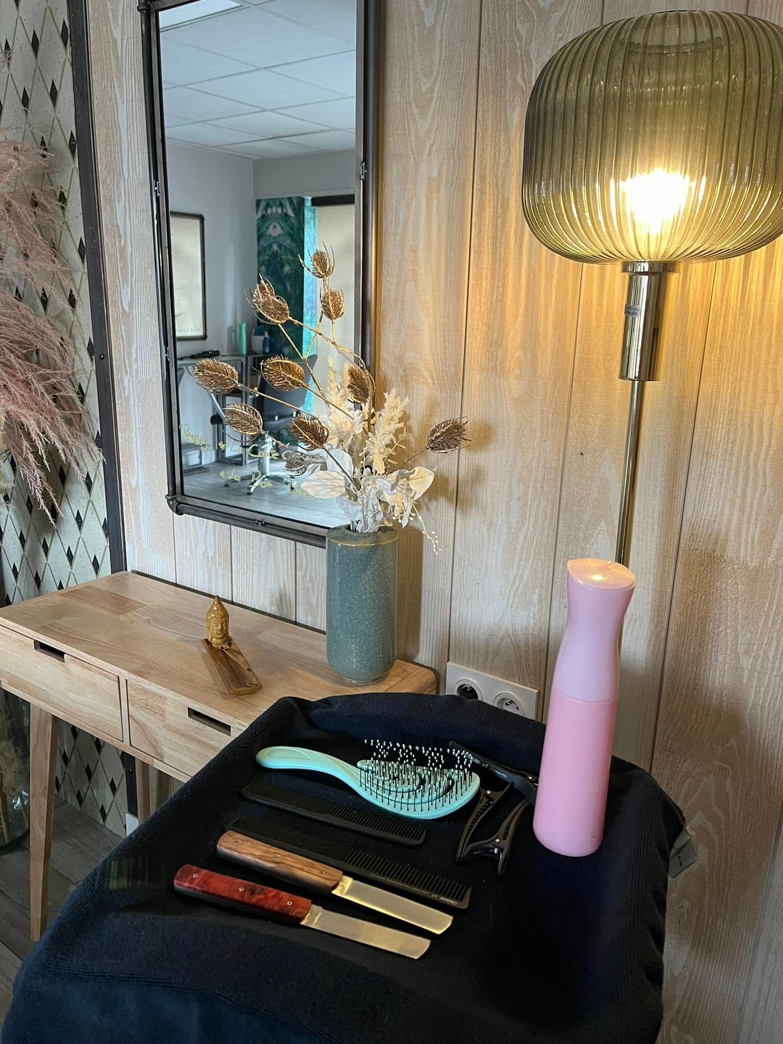 Une table avec des brosses, des peignes, une lampe et un vase de fleurs dessus.