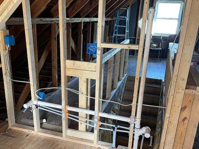 Interior view of unfinished construction in an attic. Framing with electrical boxes and plumbing pipes