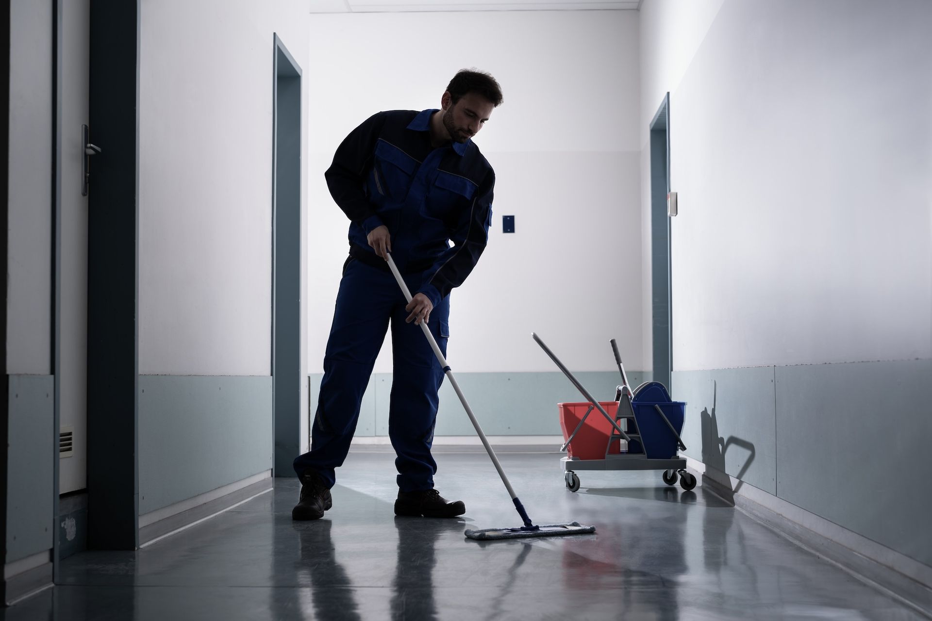 A man is cleaning a desk in an office with a spray bottle.