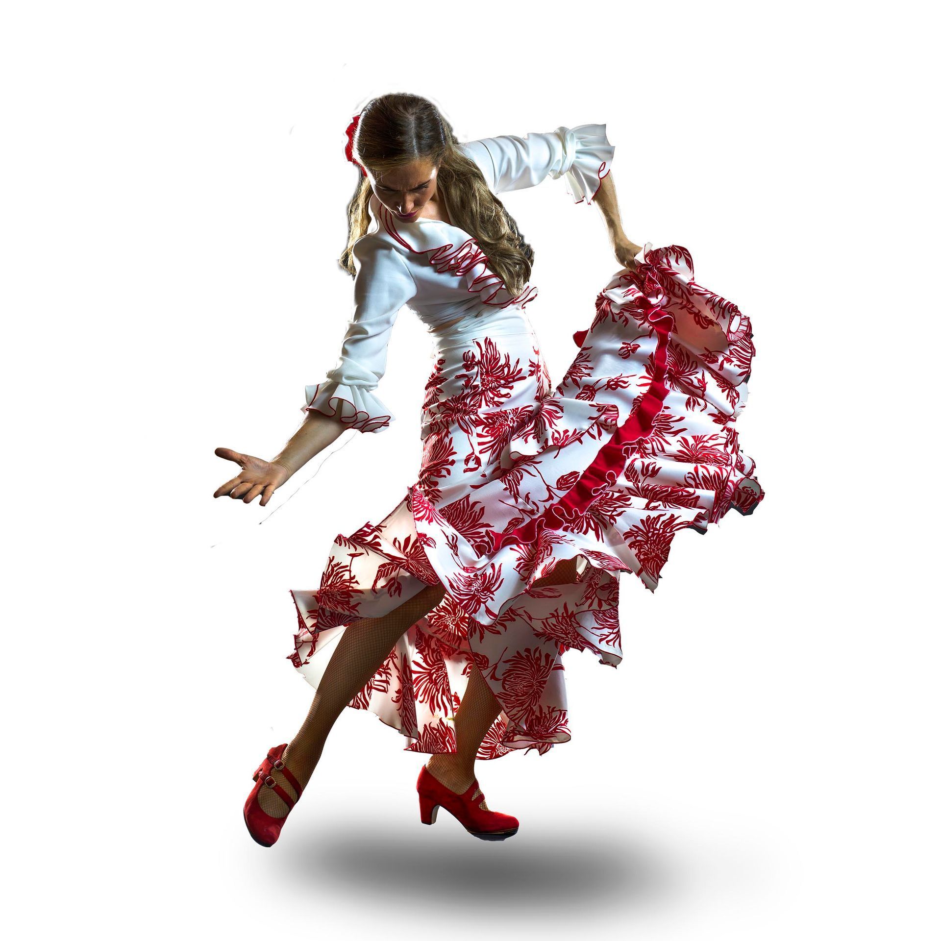 Danseuse en chemisier blanc et jupe à motifs rouges, posant en plein pas sur fond blanc
