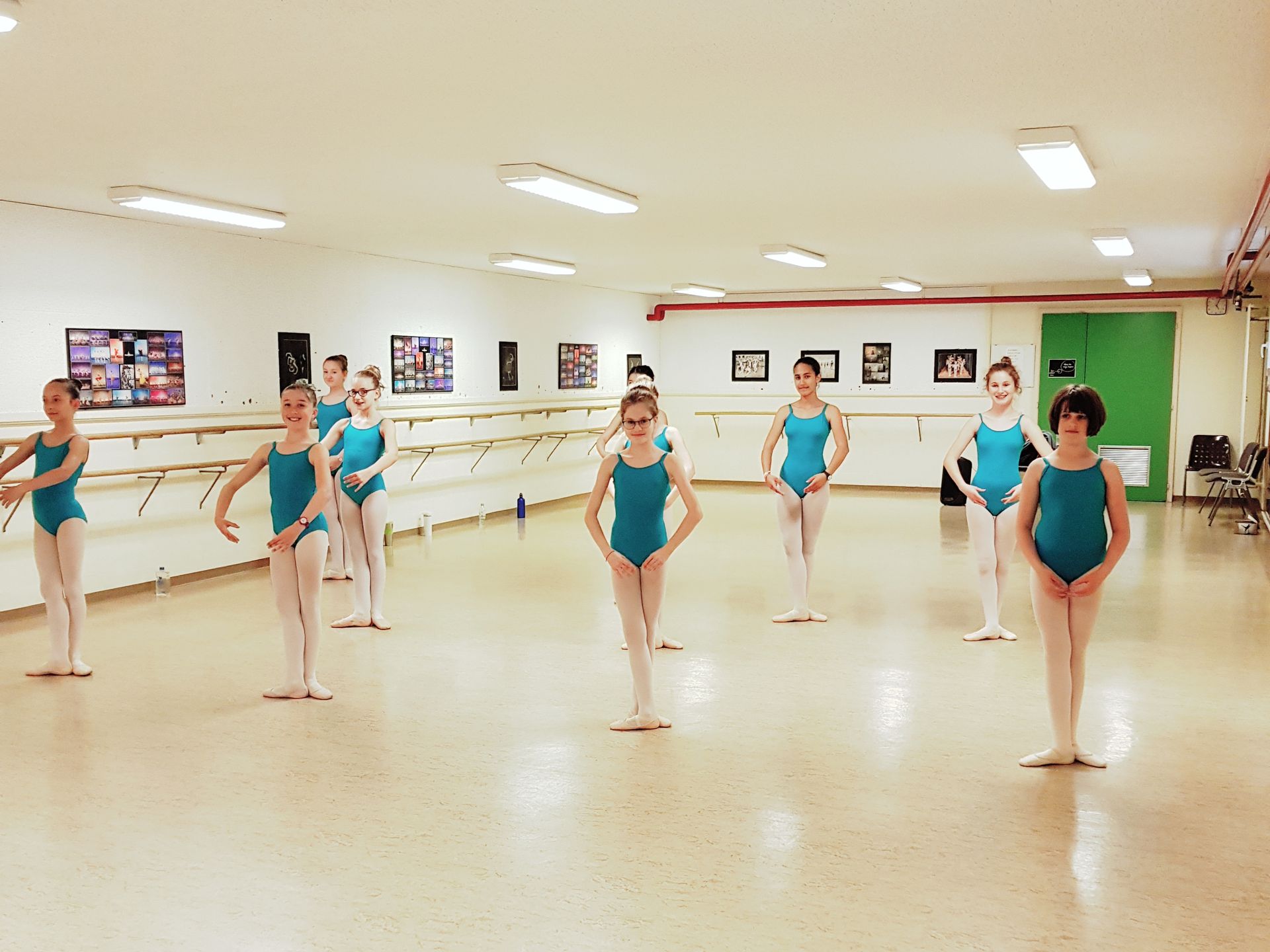 Un professeur de ballet ajuste le pied d'une jeune danseuse à la barre dans un studio