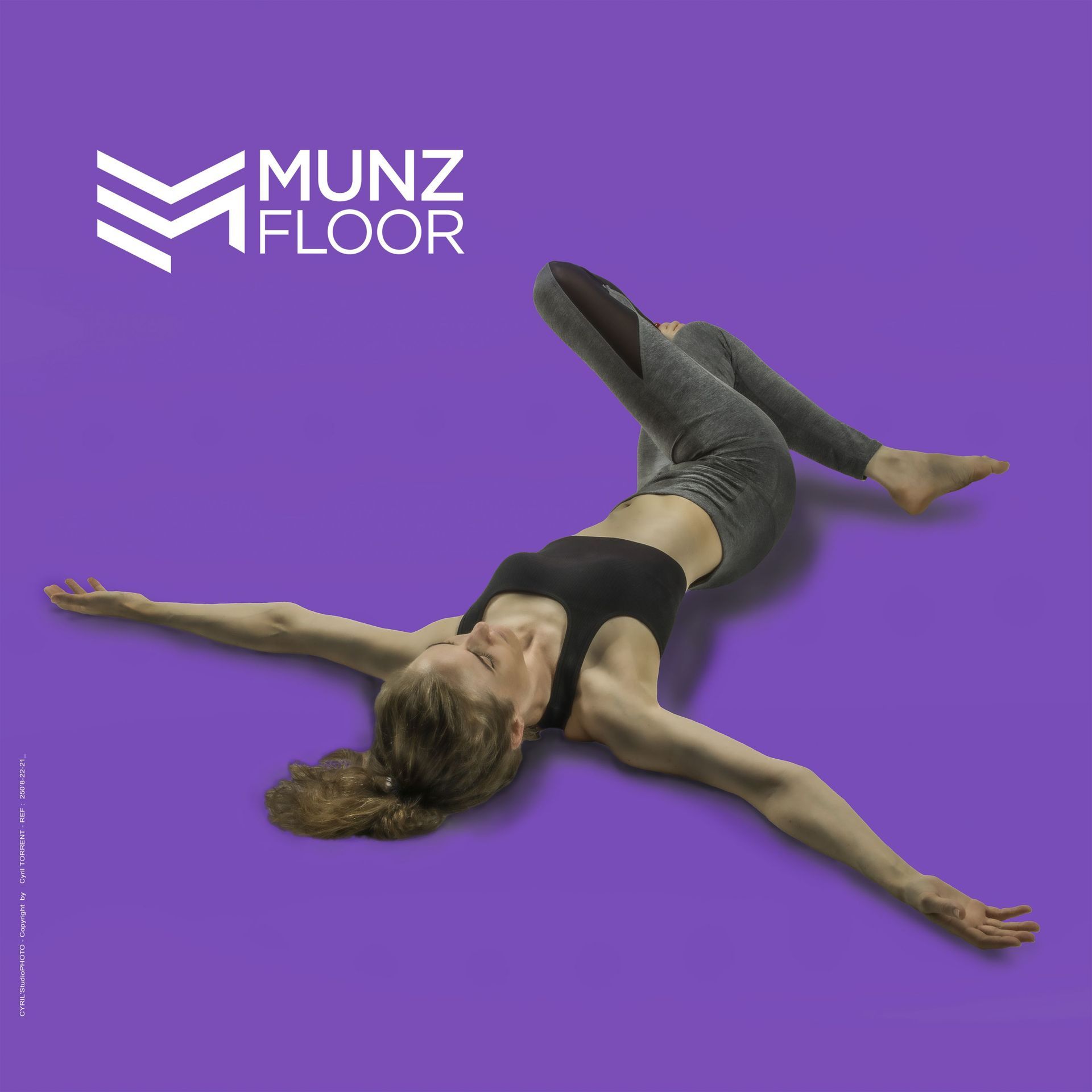 Femme allongée sur un sol violet à côté du logo Munz Floor, les bras et les jambes étendus.