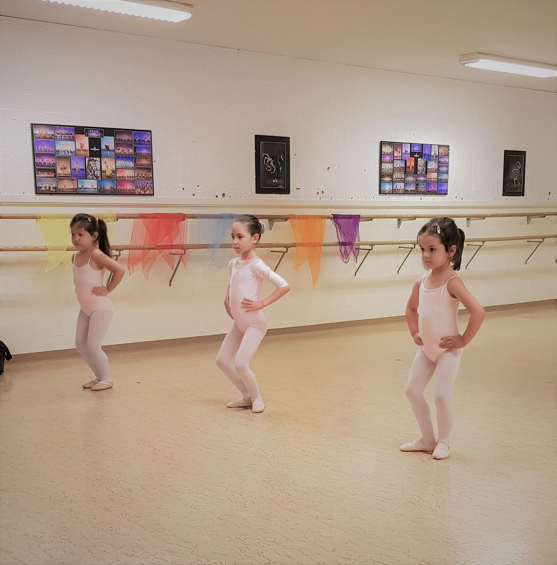 Cours de ballet : le professeur ajuste le pied d'une jeune danseuse à la barre.