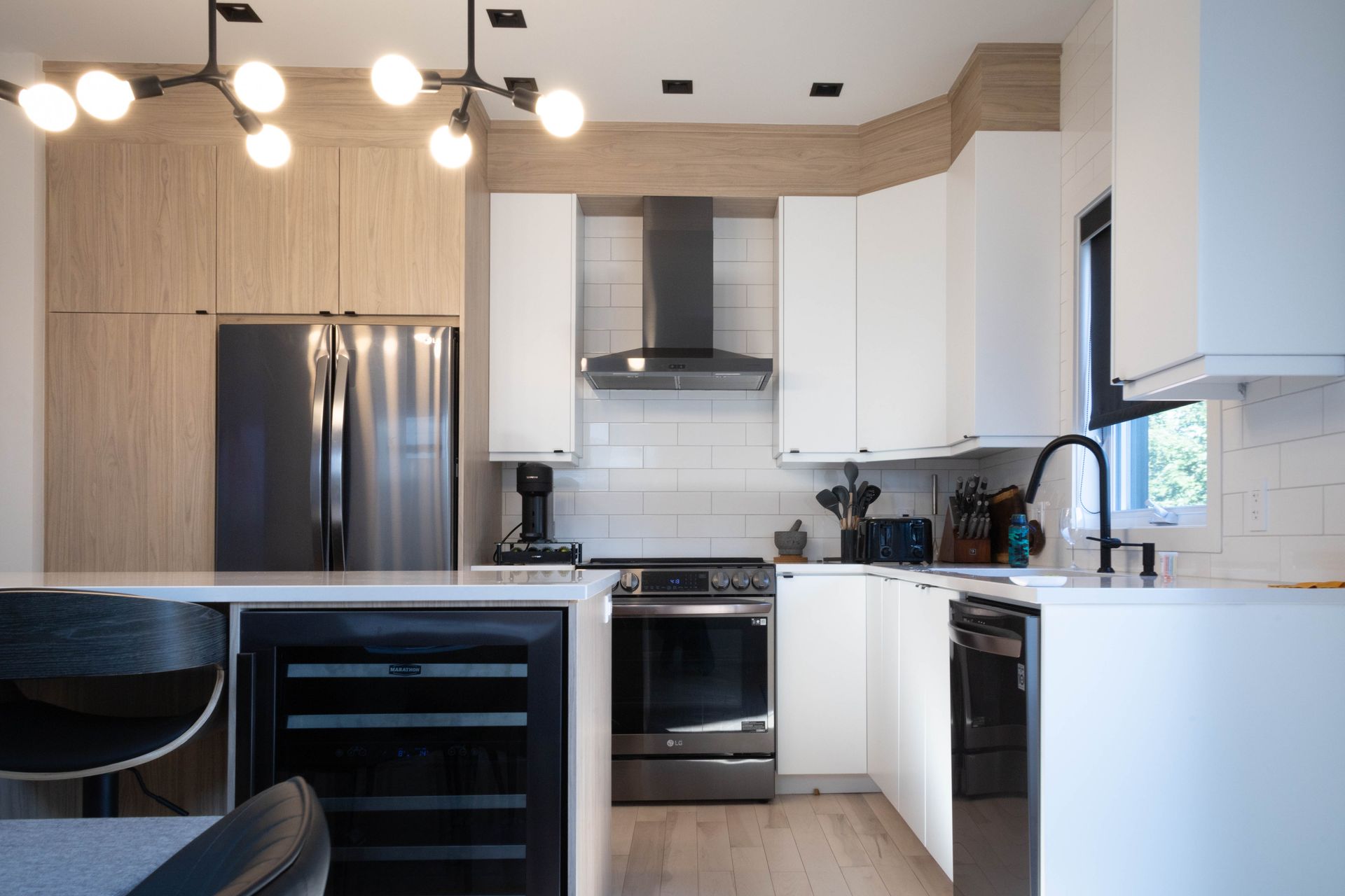 Cuisine moderne avec armoires blanches, appareils électroménagers en acier inoxydable et robinet noir.
