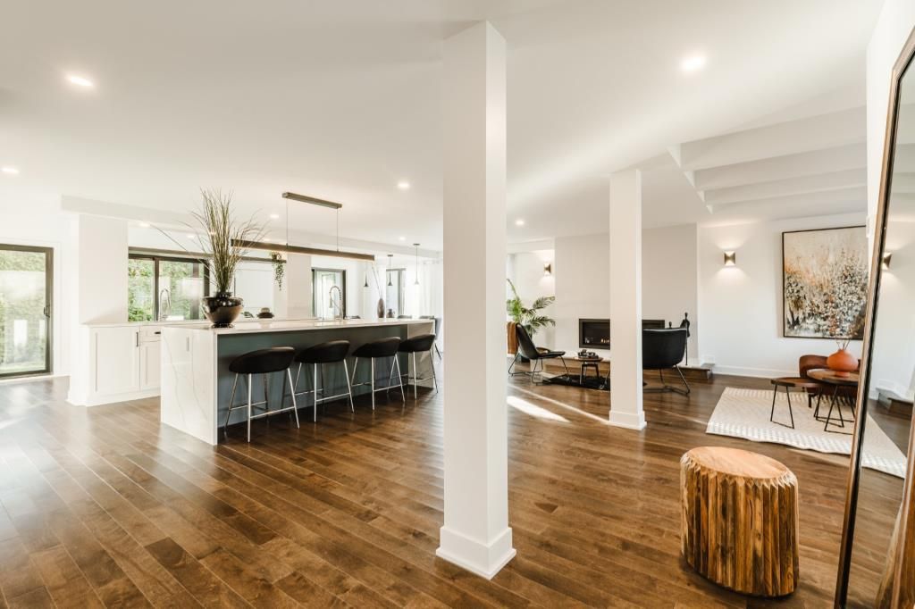 Espace de vie à aire ouverte avec îlot de cuisine, planchers de bois franc et grand miroir.
