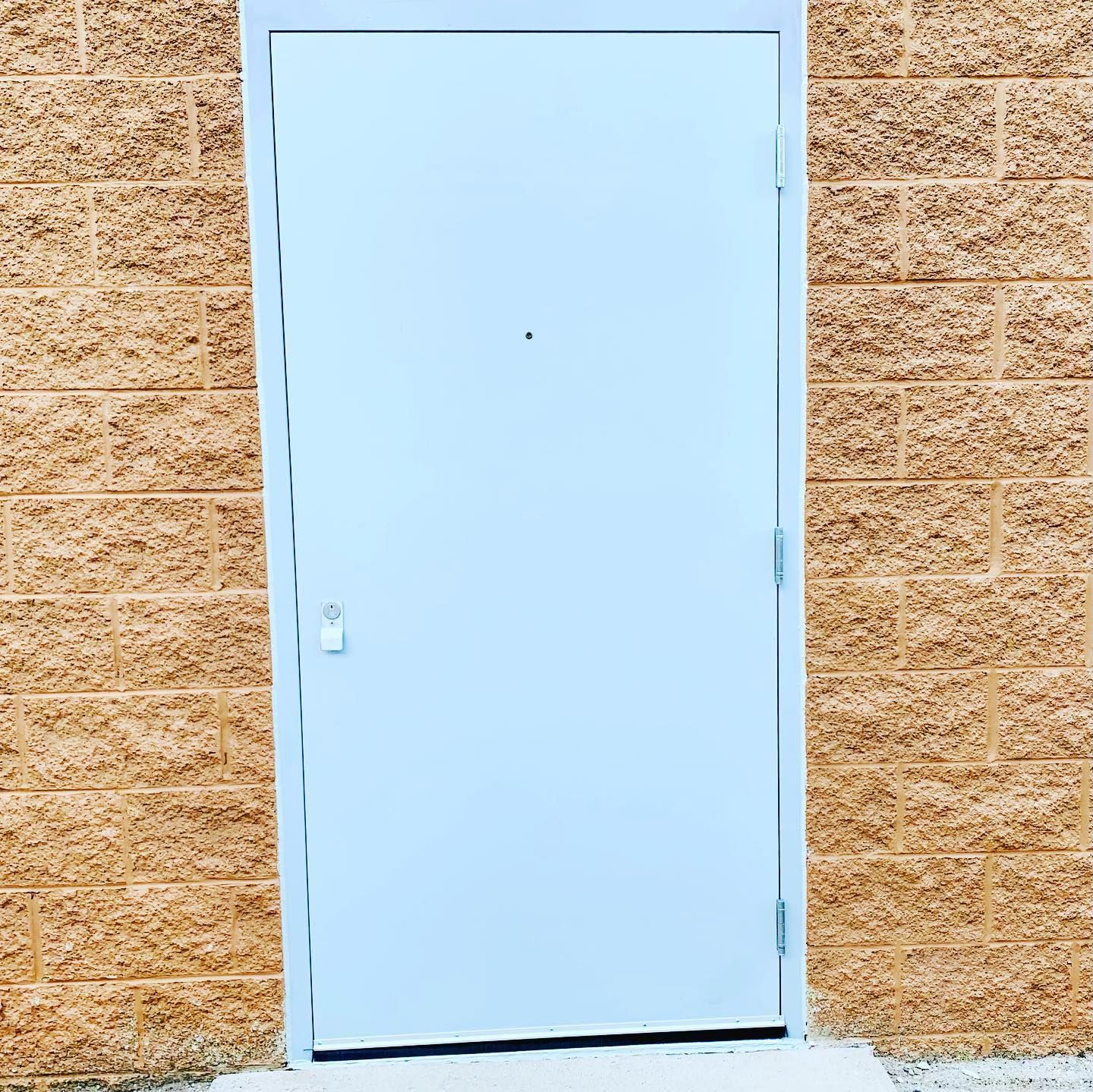 Light blue metal door set in a tan brick wall.