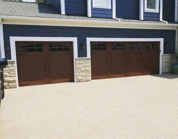 Brown garage doors on a blue house with stone accents and a concrete driveway.