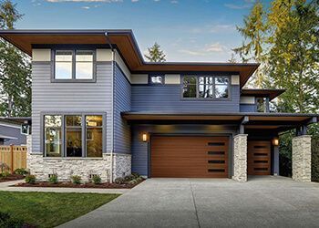 Modern two-story house with blue and brown exterior, stone accents, and a two-car garage.