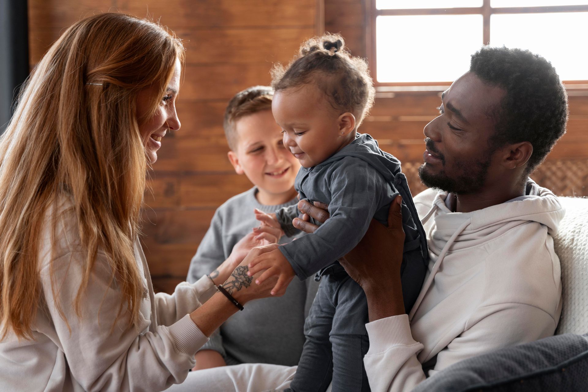 A family is sitting on a couch holding a baby.