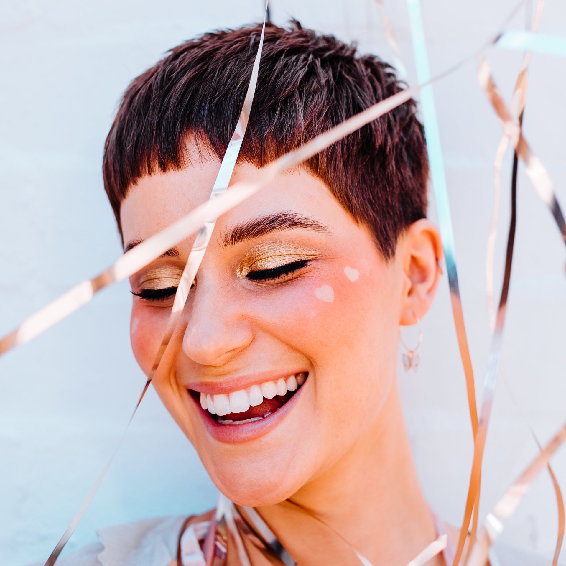 A woman with short hair is smiling and holding confetti in her hand.