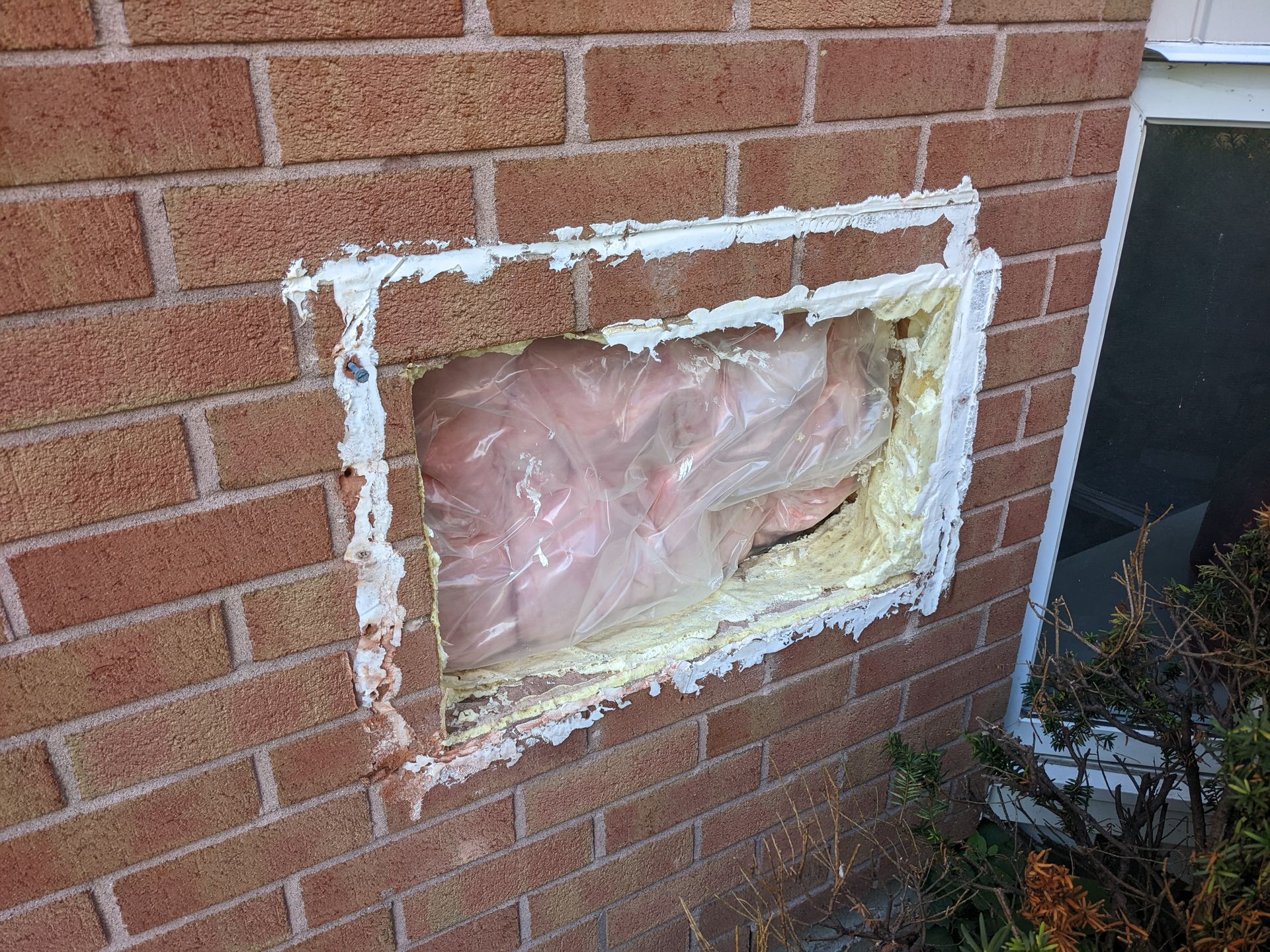 Un mur de briques avec un trou et une fenêtre.