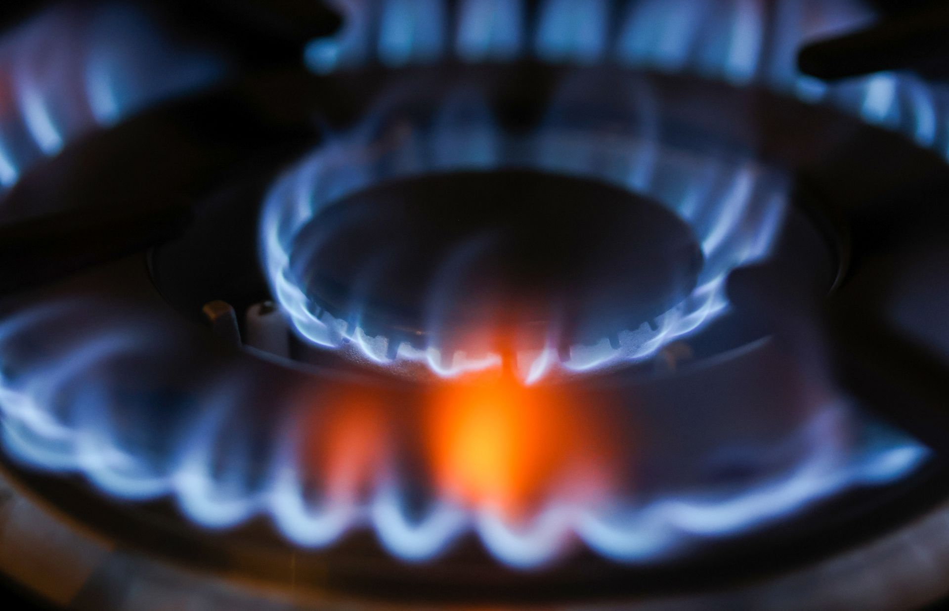 un primo piano di un fornello a gas con fiamme blu e rosse
