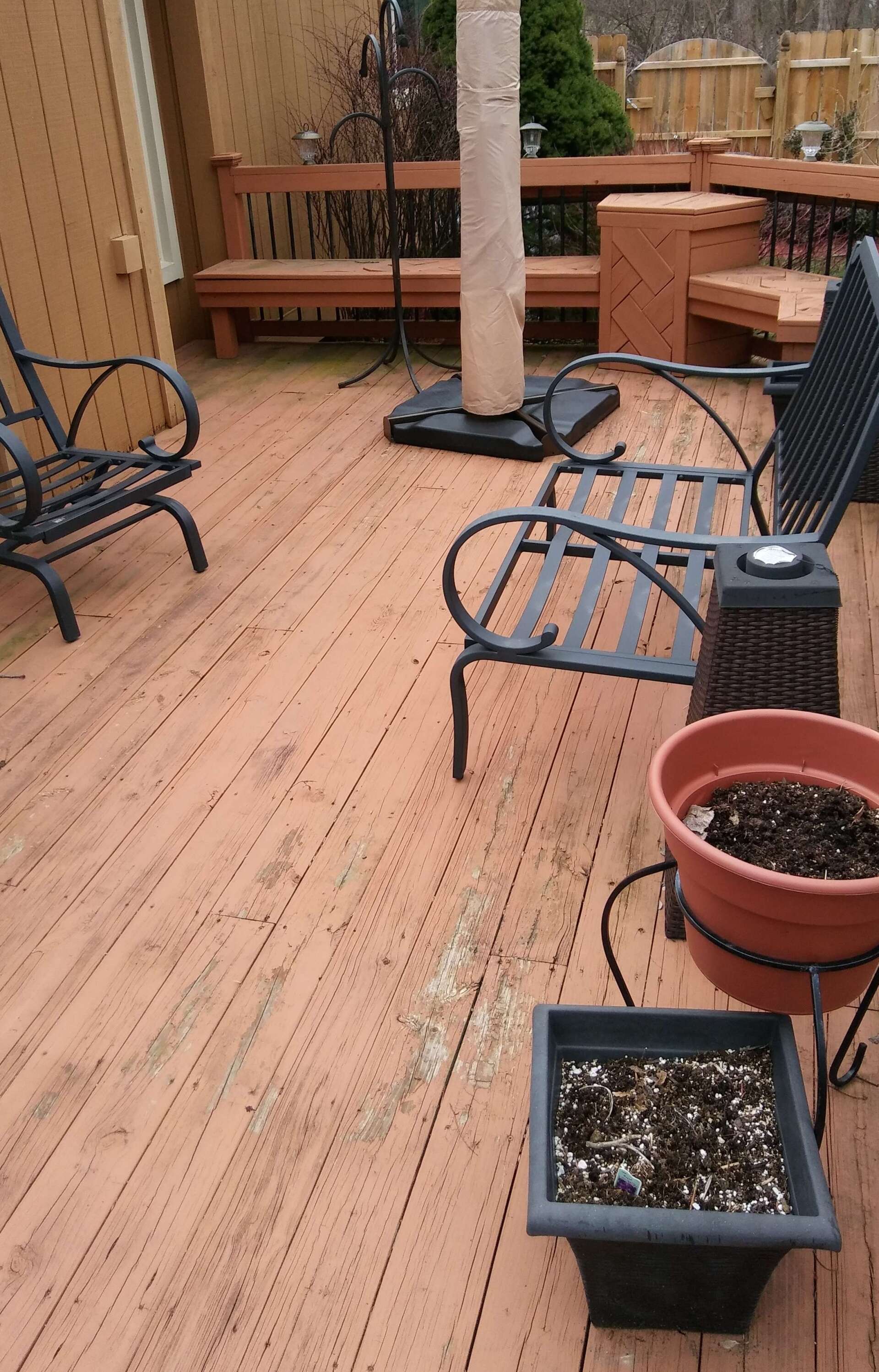 A wooden deck with chairs and potted plants on it