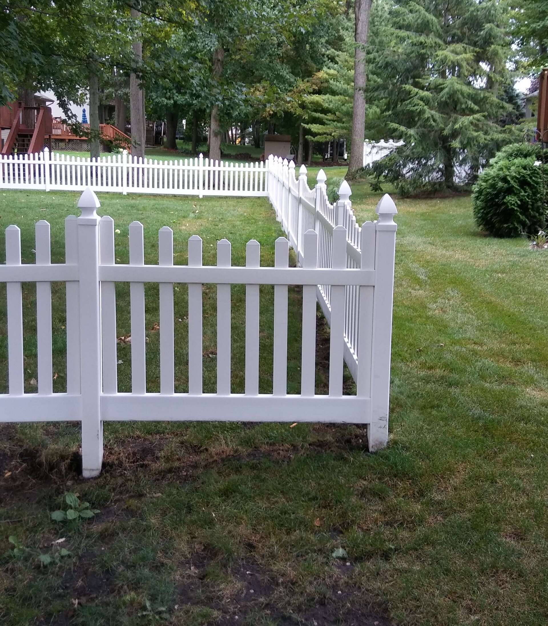A white picket fence surrounds a lush green yard.