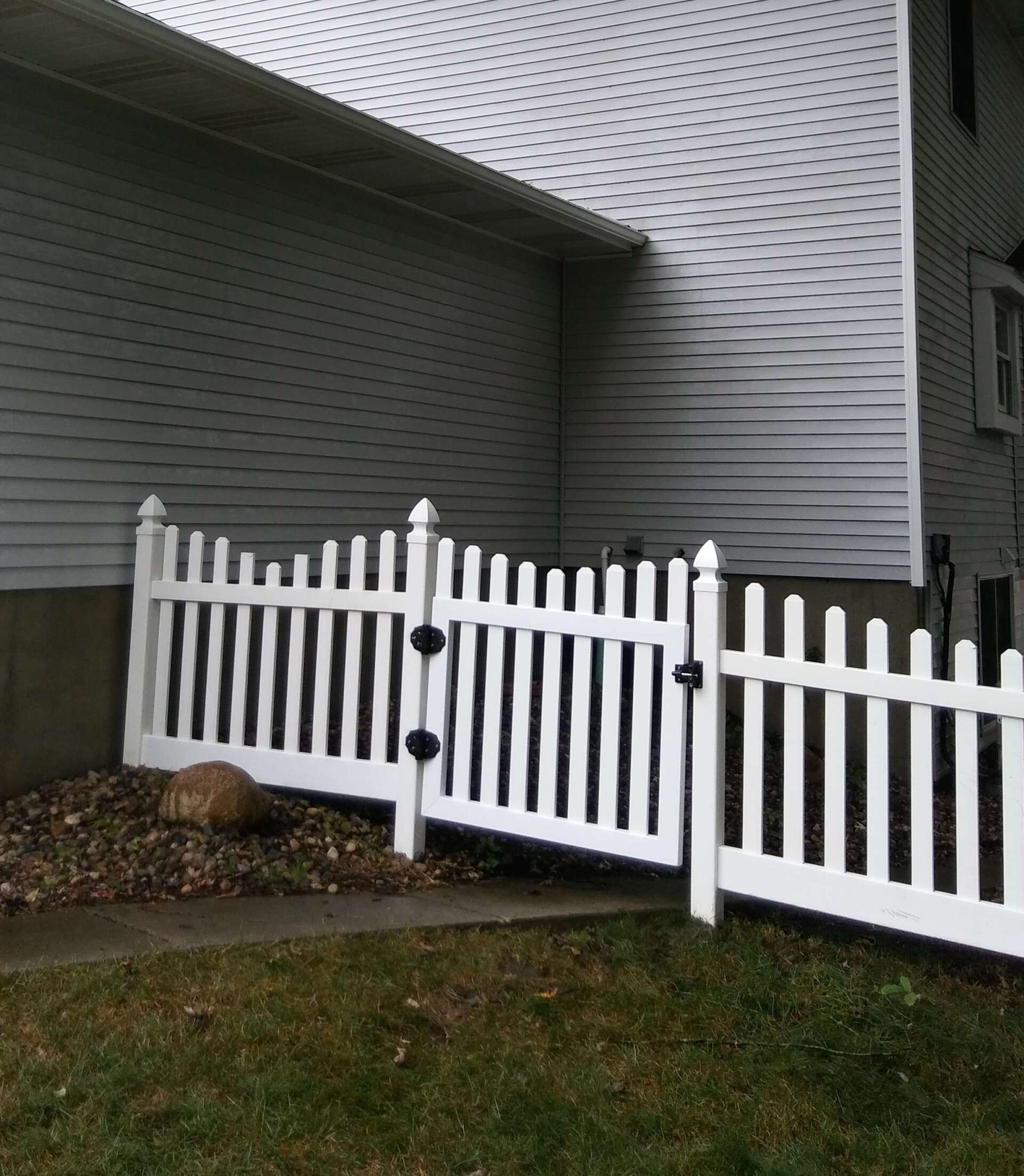 A white picket fence is in front of a white house.