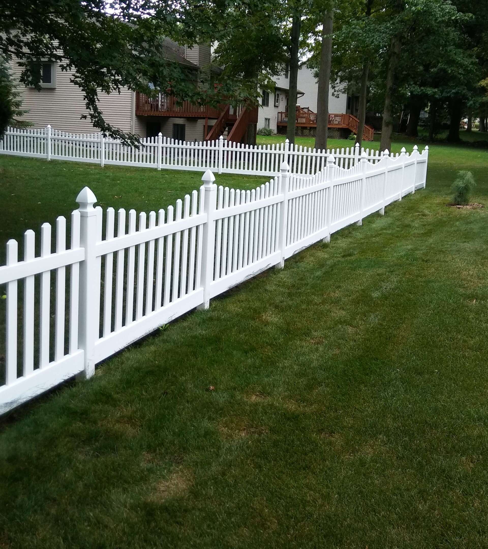 A white picket fence surrounds a lush green yard