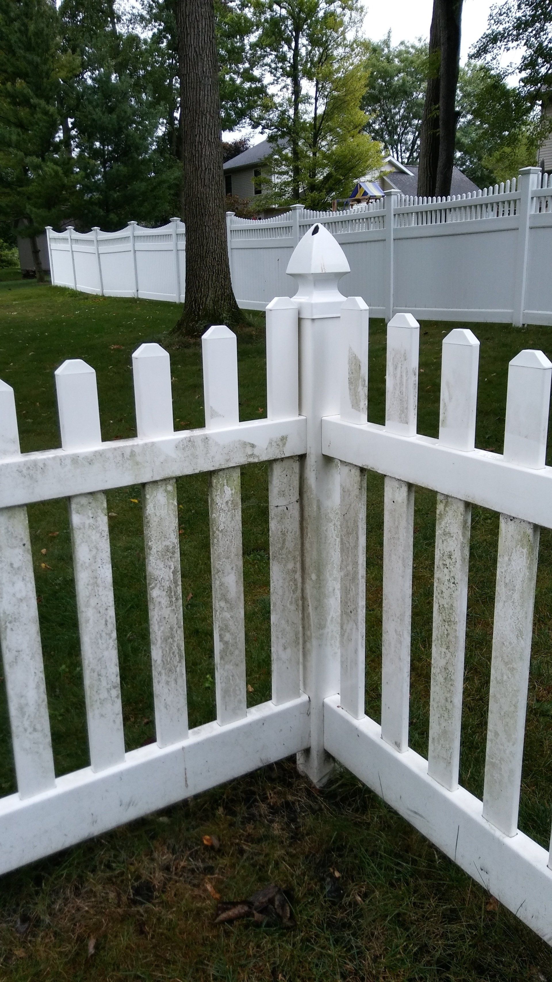 A white picket fence is sitting on top of a lush green field.