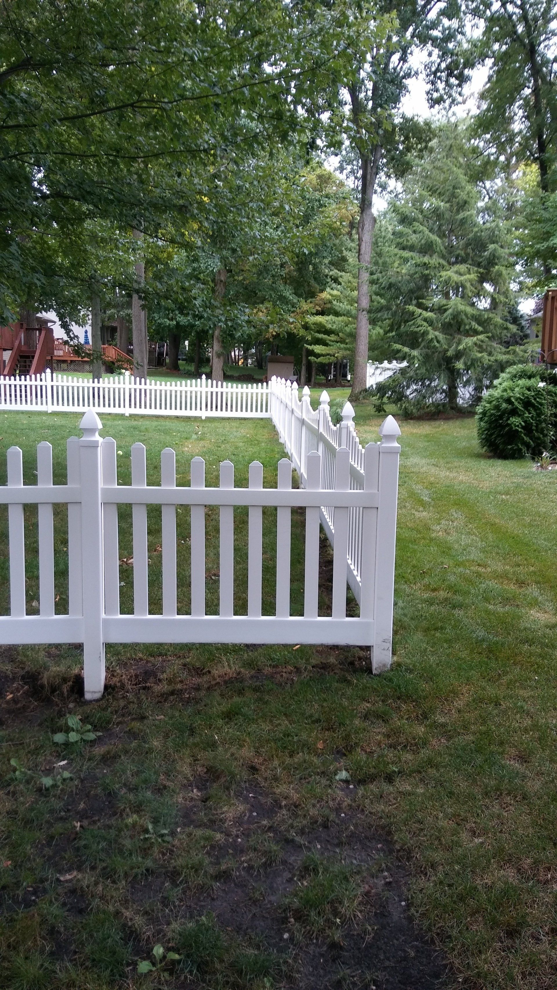 A white picket fence surrounds a lush green yard.