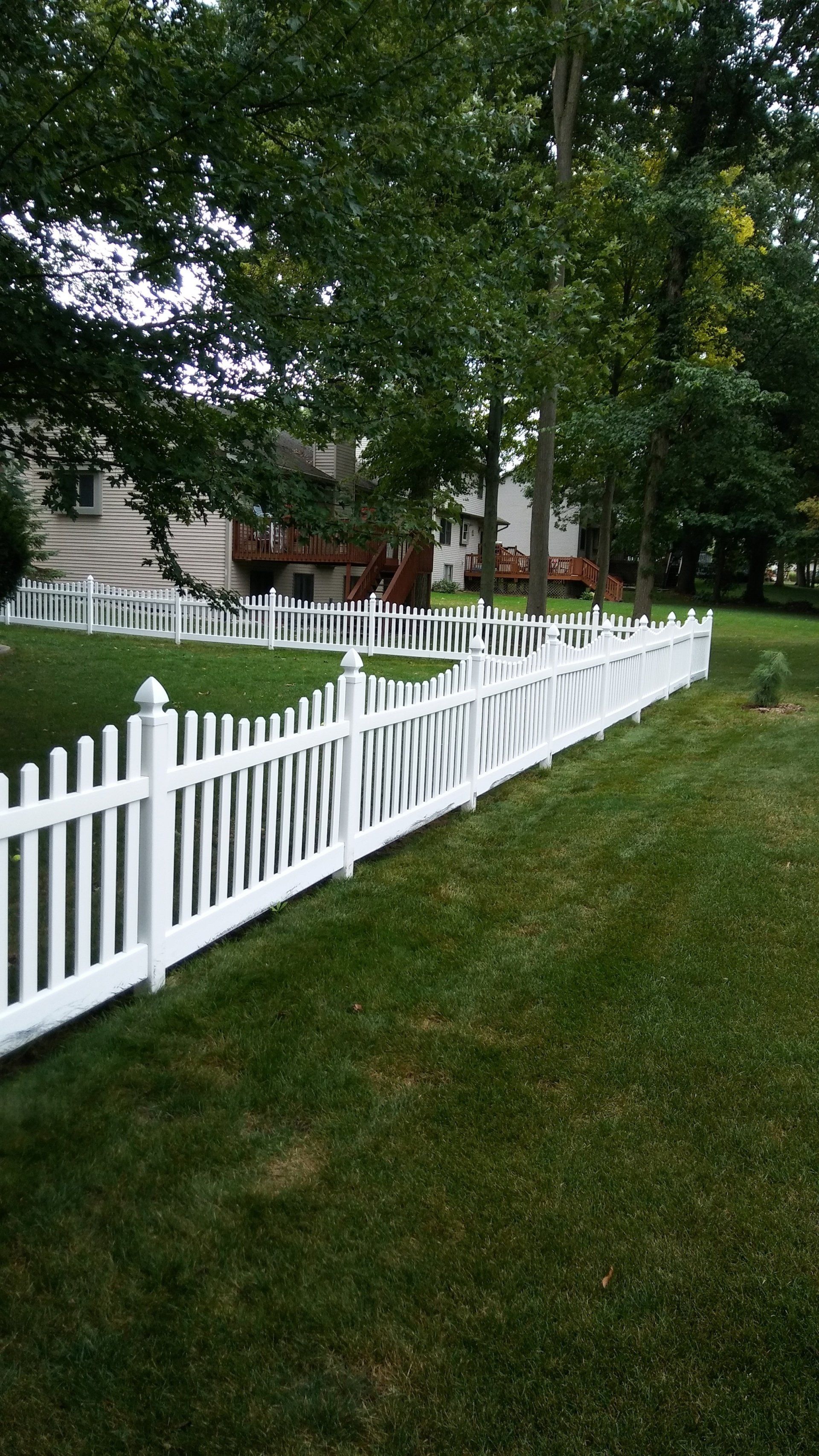 A white picket fence surrounds a lush green yard.