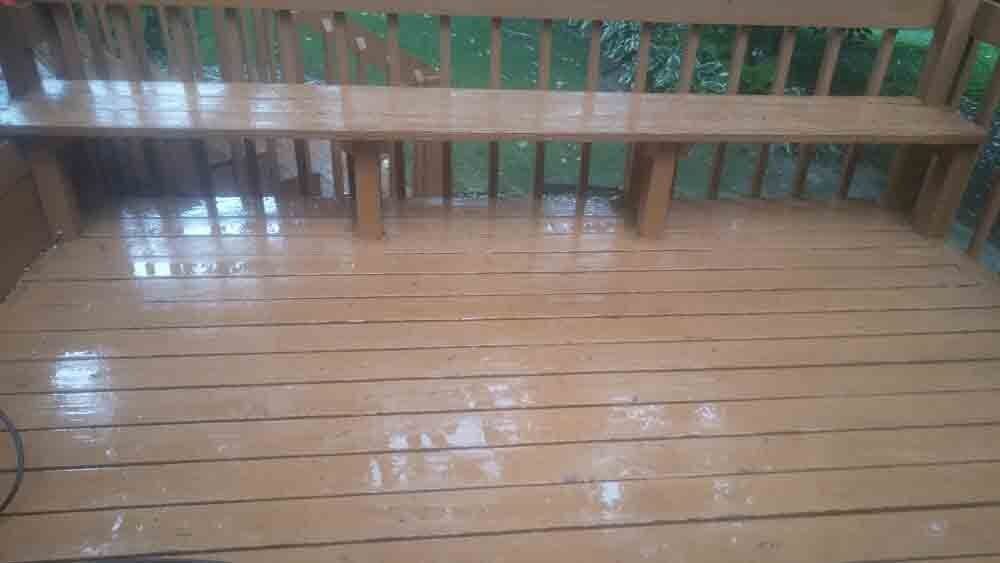 A wooden bench is sitting on top of a wooden deck.
