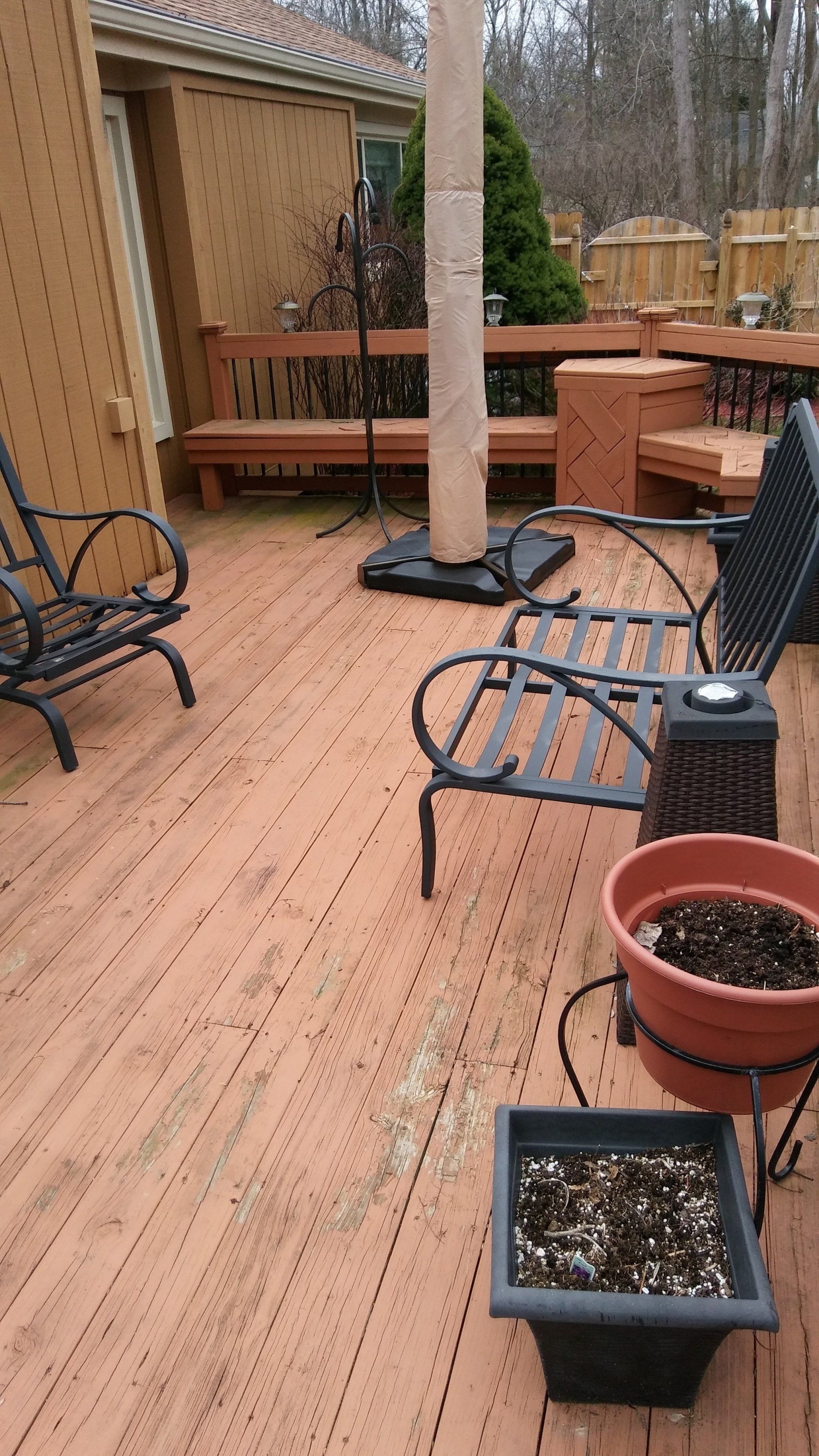 A wooden deck with chairs and potted plants on it.