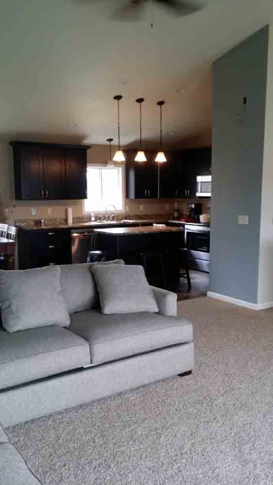 A living room with a couch and a kitchen in the background.