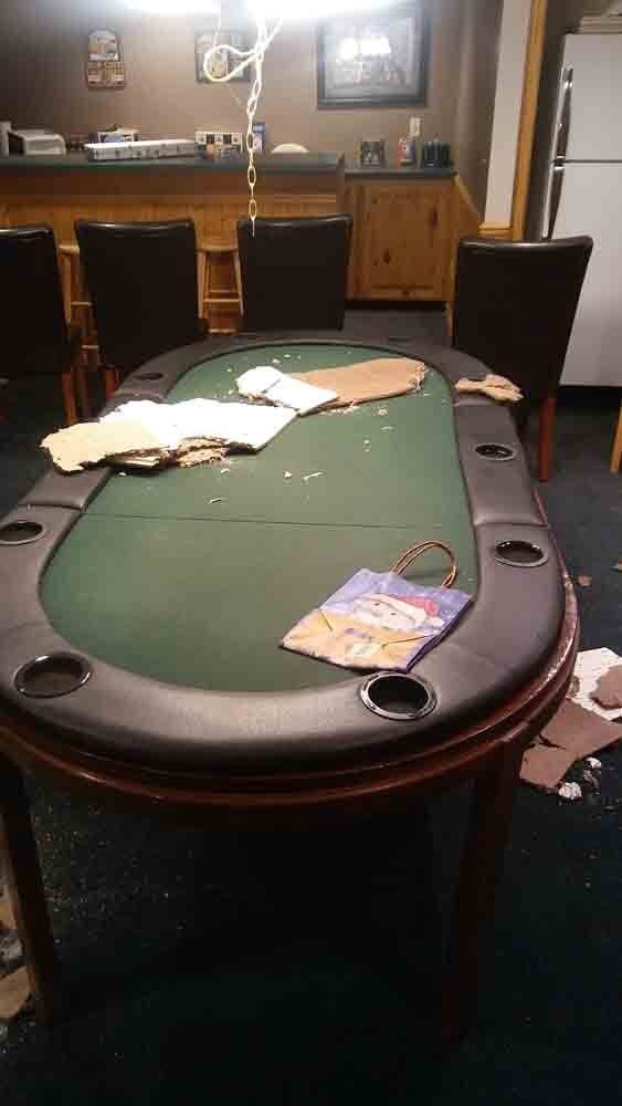 A poker table in a room with chairs and a refrigerator.