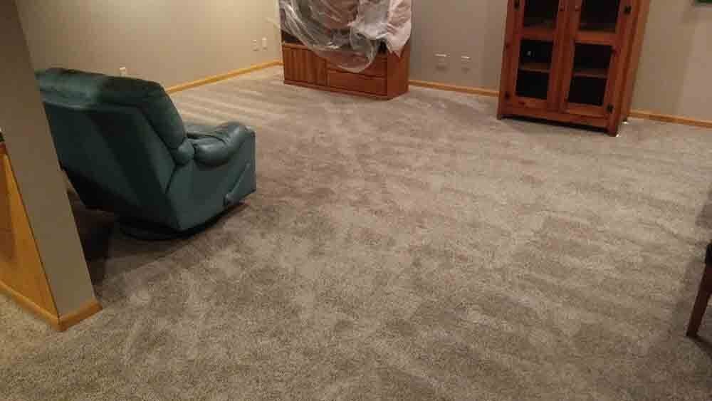 A living room with a blue recliner and a carpeted floor.