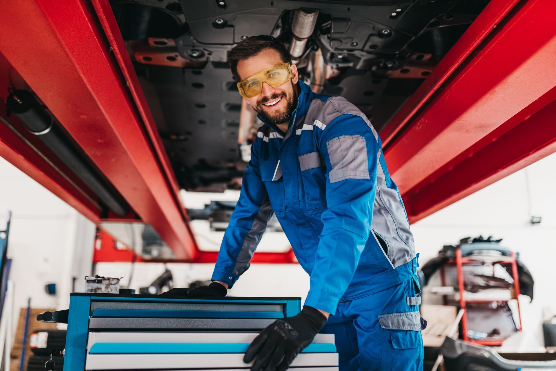 A professional mechanic working in the undercarriage of a red car.