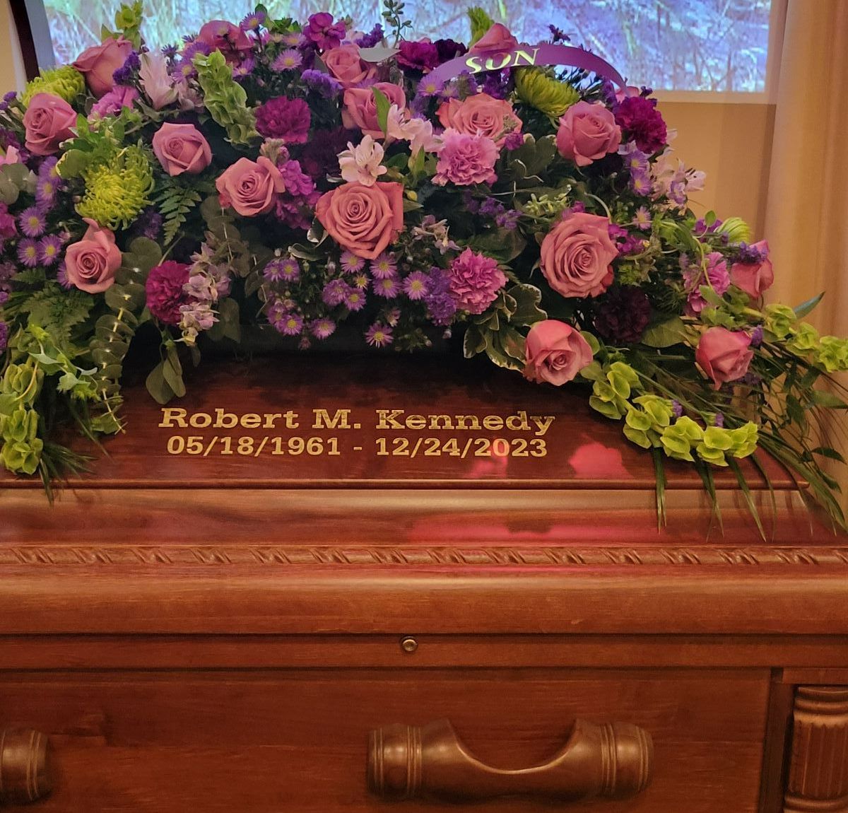 a woman is holding a red rose in front of a casket.