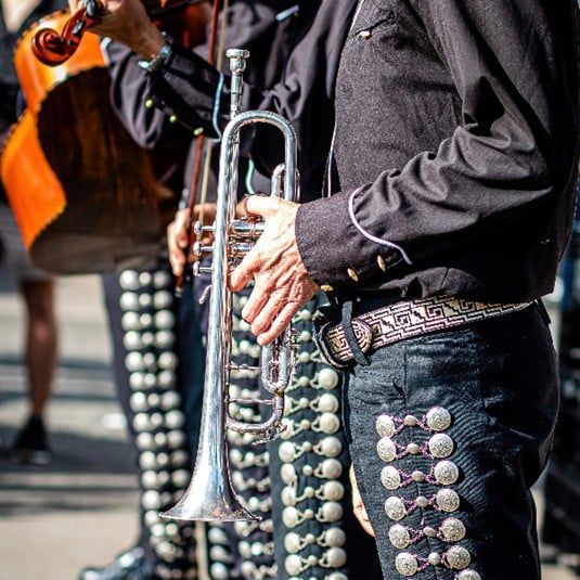 A man is playing a violin and a trumpet in a band.