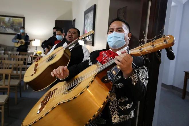 A man wearing a mask is holding two guitars.