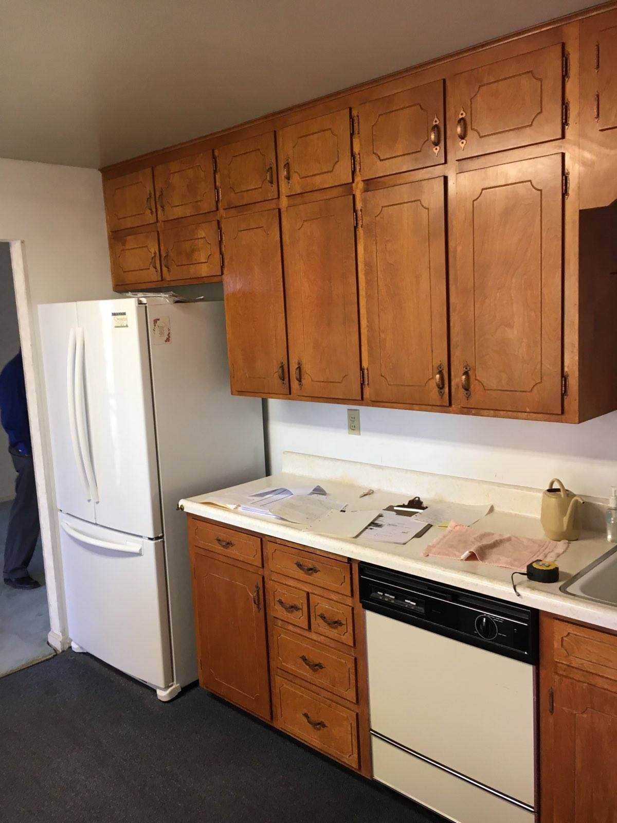 Kitchen with wooden cabinets, white refrigerator, and black and white appliances.