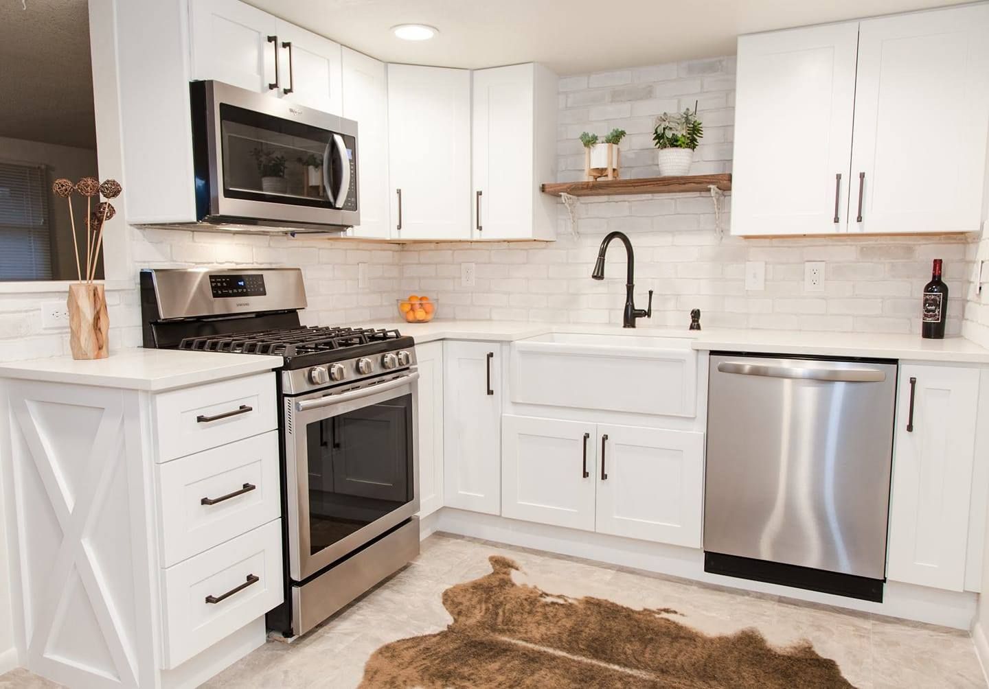 White kitchen with stainless steel appliances and wood accents, including a rug.