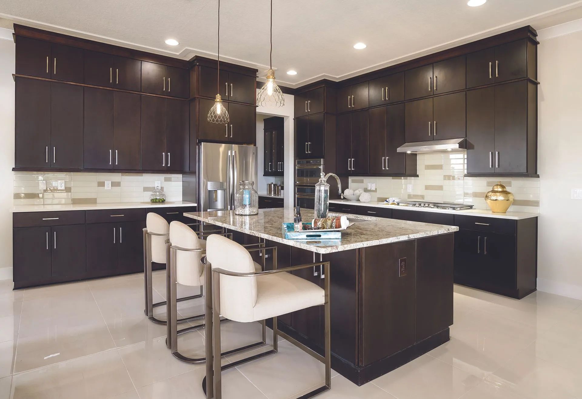 Modern kitchen with dark cabinets, white countertops, island seating, and stainless steel appliances