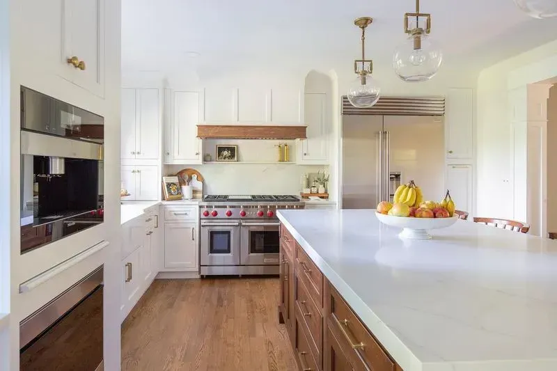 Bright white kitchen with stainless steel appliances, wood accents, and a large island.