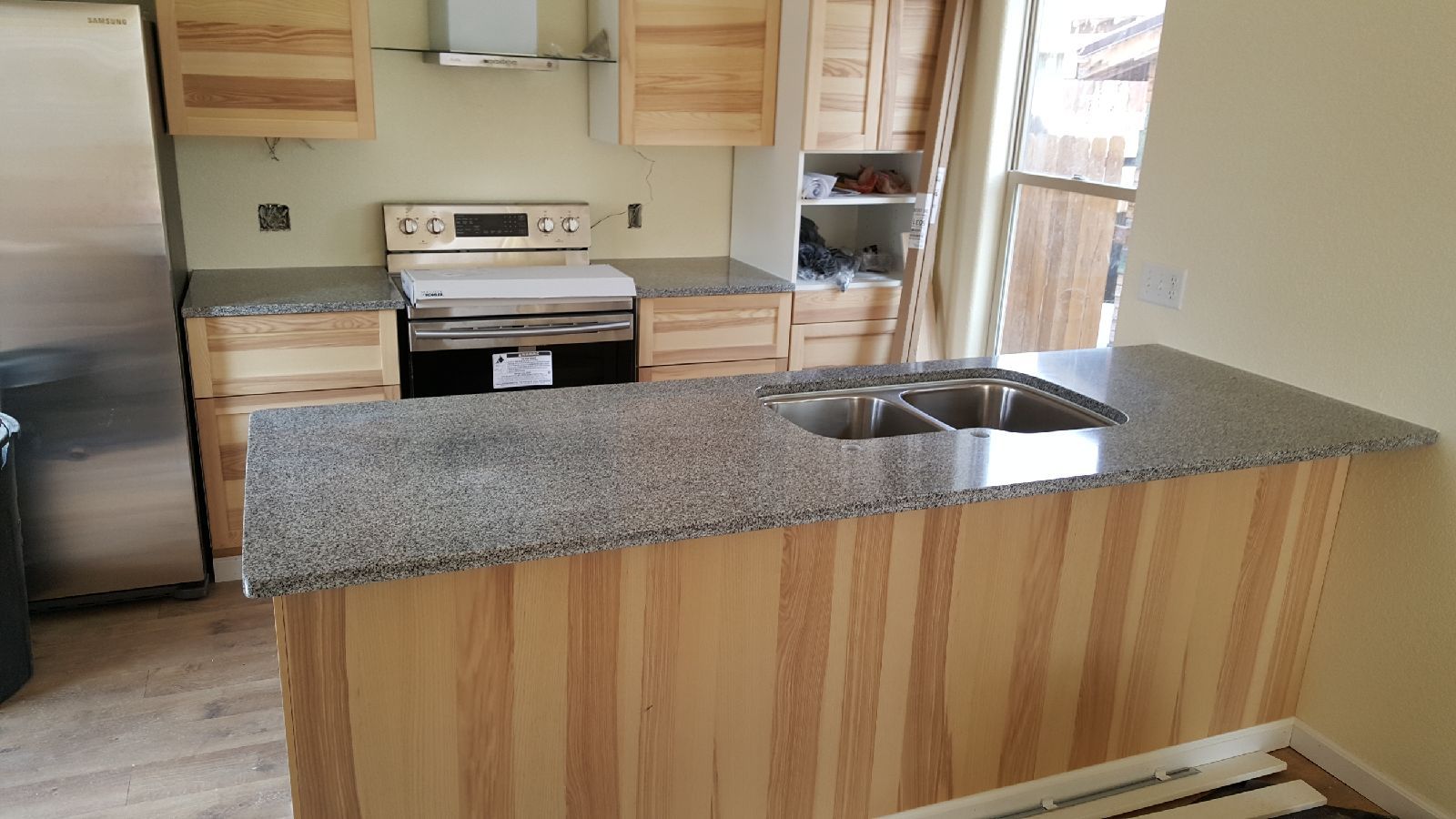 Kitchen with light wood cabinets, granite countertops, and a stainless steel sink.
