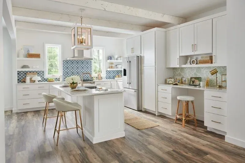 Bright white kitchen with a center island, white cabinets, and wooden floors.