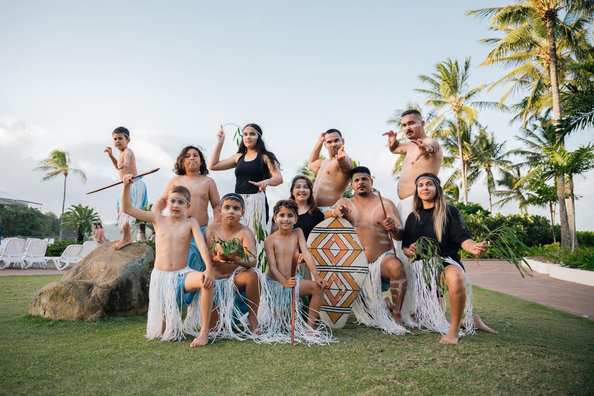 A group of people are posing for a picture in front of palm trees.