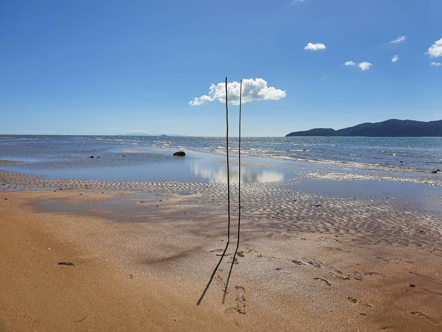 A couple of poles sitting on top of a sandy beach next to the ocean.