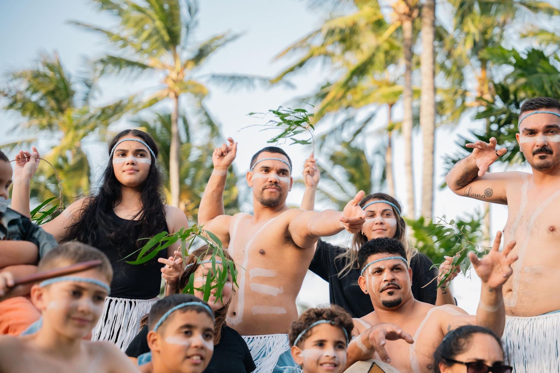 A group of people are standing next to each other in front of palm trees.
