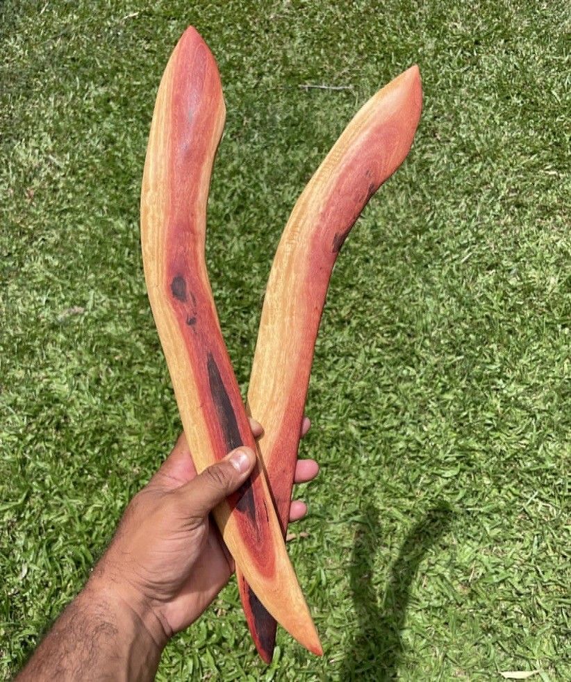 A person is holding two wooden sticks in their hand.
