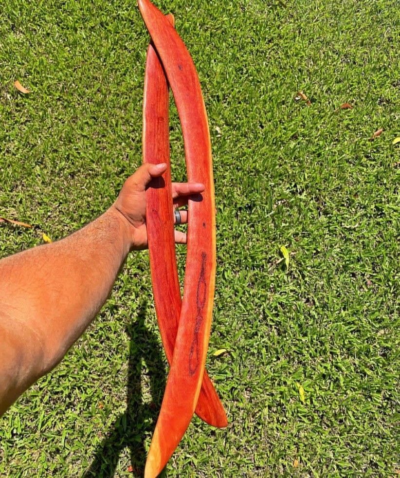 A person is holding a red bow in their hand in the grass.
